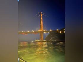 A stunning night view of the iconic Golden Gate Bridge illuminated against the dark sky, showcasing the beauty of this landmark from the water.