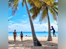 A family enjoys a sunny day at the beach, with a sailboat visible in the background — perfect for a fun-filled day of swimming and relaxation.