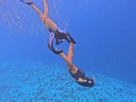 Two snorkelers dive underwater, showcasing the vibrant marine life and clear blue waters — an exhilarating experience for adventure seekers.