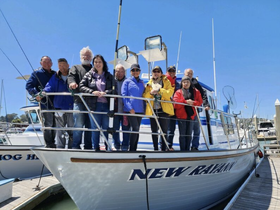 A cheerful group of friends poses together on the deck of the 'New Raven' boat, ready for a memorable day on the water.
