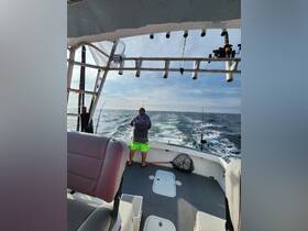 A fisherman stands on the deck of a boat, casting lines into the open sea — an ideal scene for fishing enthusiasts enjoying a day on the water.