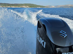A dynamic shot of a Suzuki outboard motor in action, creating a wake as the boat speeds through clear waters, showcasing the thrill of boating adventures.