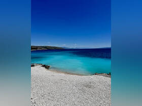 A stunning view of a serene beach with crystal-clear turquoise waters and a picturesque coastline, perfect for relaxation and exploration.