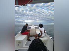 Two individuals relax on the deck of a boat, enjoying the serene waters and cloudy skies — a perfect moment for a family outing or a leisurely cruise.