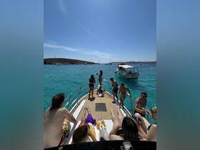 A lively group enjoys a sunny day on the boat, celebrating with drinks and snacks while surrounded by crystal-clear waters — the perfect backdrop for a summer getaway.