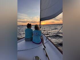 Two friends enjoy a serene sunset while sailing, creating a perfect backdrop for memorable moments on the water.