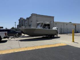 A sleek speedboat is docked on a trailer outside a facility, showcasing its modern design and readiness for adventure.