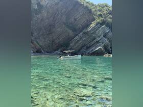 A serene view of a boat anchored in crystal-clear waters, surrounded by stunning rocky cliffs — perfect for exploring hidden coves and enjoying nature.
