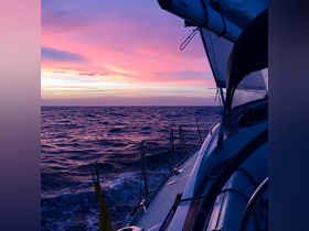 A stunning sunset view from the deck of a sailboat, showcasing vibrant colors over the ocean — perfect for romantic evening cruises.