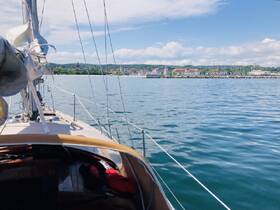 A scenic view from the deck of a sailboat, showcasing the tranquil waters and a picturesque shoreline in the background — perfect for sailing enthusiasts and coastal adventures.