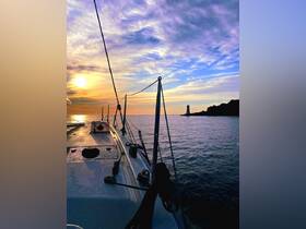 A stunning view from the deck of a yacht at sunset, showcasing the tranquil waters and a distant lighthouse — perfect for serene evening cruises.
