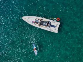 Aerial view of a group enjoying a day on the water, with a paddleboarder near a boat — perfect for summer adventures and water sports.