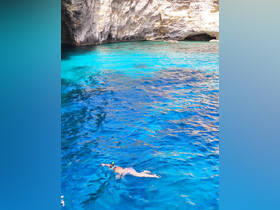 A snorkeler explores the vibrant blue waters near a stunning cave, showcasing the beauty of underwater adventures and scenic destinations.