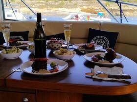 A beautifully arranged dining table on a boat featuring gourmet dishes and drinks, perfect for a luxurious onboard dining experience.