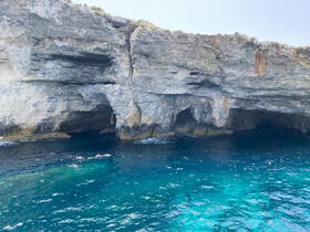 A stunning view of rocky cliffs and caves along the coastline, showcasing the natural beauty of the area — perfect for eco tours and scenic boat trips.