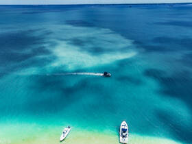Aerial view of boats cruising through stunning turquoise waters, showcasing the beauty of a perfect day on the water.