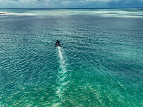Aerial view of a speedboat cruising through crystal-clear turquoise waters, showcasing the beauty of the ocean and the vessel in motion.