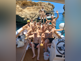 A lively group of friends enjoys a sunny day on a boat, celebrating and having fun in the beautiful waters — perfect for summer outings and memorable adventures.