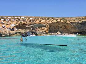 A lively scene with guests enjoying a sunny day by the beach, with a boat anchored nearby, perfect for swimming and relaxation.