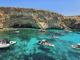 A vibrant scene of multiple boats enjoying the crystal-clear waters near a stunning coastline, perfect for a day of exploration and relaxation.