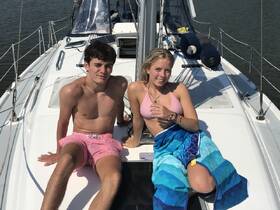 A young couple relaxes on the deck of a sailboat, enjoying the sun and water — a perfect moment for summer adventures on the water.