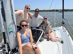 A cheerful group of friends enjoys a sunny day sailing, capturing the essence of summer fun on the water.