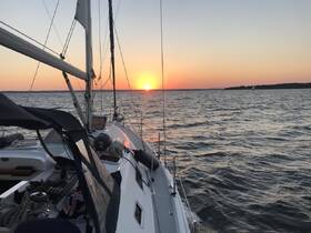 A serene sunset view from the deck of a sailboat, showcasing the tranquil waters and vibrant sky — perfect for evening sailing adventures.