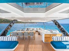 A luxurious interior view of a yacht's dining area, featuring elegant seating and a well-equipped kitchen space, perfect for entertaining guests while enjoying stunning ocean views.