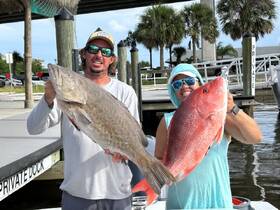 Two anglers proudly display their impressive catch at the dock, showcasing a successful fishing trip — a perfect moment for fishing enthusiasts.