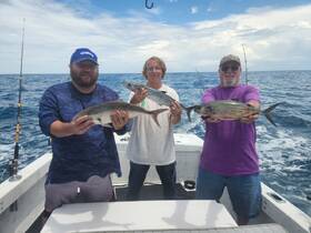 A group of anglers proudly display their catch while fishing on the open ocean, showcasing a successful day out on the water.