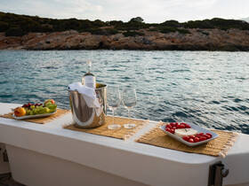 An elegant setup featuring a bottle of wine, fresh fruit, and snacks on a boat, perfect for a relaxing day on the water.