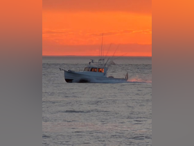 A fishing boat navigates through shimmering waters at sunset, creating a picturesque scene perfect for maritime enthusiasts.