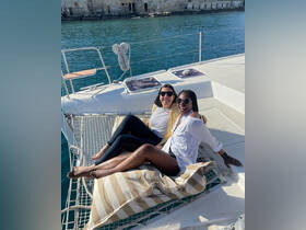 Two friends relax on a catamaran, enjoying the sun and beautiful waters — perfect for a day of fun and relaxation on the sea.