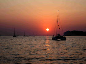 A serene sunset view featuring multiple sailboats on the water, creating a picturesque scene perfect for evening cruises.