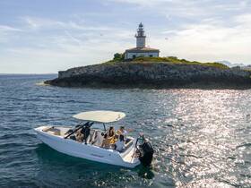 A group enjoys a beautiful day on a boat near a picturesque lighthouse, capturing the essence of a perfect boating adventure.