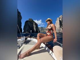 A woman enjoys the sun on a boat near stunning rock formations, capturing the essence of a perfect day on the water.