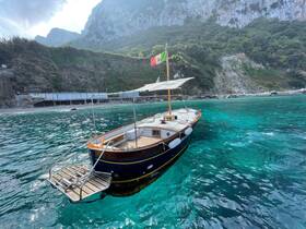 A beautiful wooden boat anchored in crystal-clear waters, surrounded by stunning coastal scenery — perfect for exploring hidden gems along the shoreline.