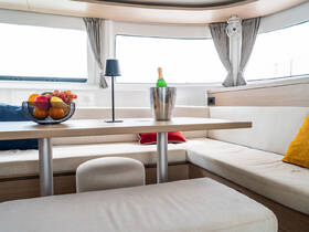 A beautifully designed interior of a boat featuring a cozy dining area with a fruit bowl and champagne, perfect for relaxing and entertaining guests on board.