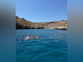 Two friends enjoy a refreshing swim in crystal-clear waters surrounded by stunning rocky cliffs — a perfect summer getaway for adventure seekers.
