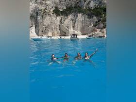 A joyful group of friends swims in the crystal-clear waters, enjoying a perfect beach day — a memorable experience under the sun.