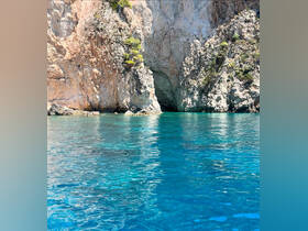 A stunning view of a rocky coastline with a cave entrance, surrounded by crystal-clear turquoise waters — a perfect destination for boat trips and exploration.