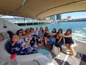 A lively group of friends celebrates on a boat with cocktails, perfect for a fun day out on the water.