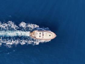 Aerial view of a sleek yacht cruising through deep blue waters, showcasing its elegant design and powerful movement.