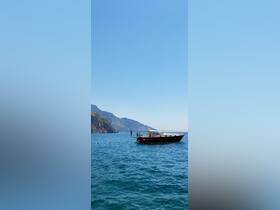 A group enjoys a sunny day on the water, with a boat anchored near a stunning coastline — perfect for swimming and relaxation.