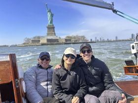 A cheerful group enjoys a boat ride with the iconic Statue of Liberty in the background, perfect for sightseeing and memorable experiences on the water.
