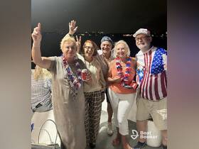 A lively group of friends celebrates together on a boat, showcasing festive attire and drinks, perfect for a fun night out on the water.