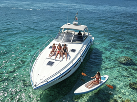 A group of friends enjoys a sunny day on a boat, with one person kayaking nearby — perfect for summer adventures and water activities.