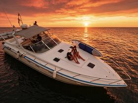 Two guests relax on the deck of a boat during a stunning sunset, with a paddleboard nearby — an ideal setting for evening cruises and memorable experiences on the water.