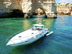 A stunning view of a yacht navigating through crystal-clear waters near dramatic rock formations, perfect for exploring coastal landscapes.