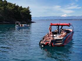 A lively group enjoys a sunny day on a boat, with some snorkeling and others relaxing on the deck — perfect for summer fun and beach parties.